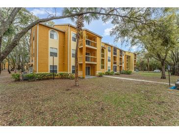 A yellow apartment building with balconies, and trees surrounding it at 5291 Images Cir # 302, Kissimmee, FL 34746