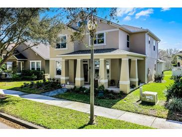 Charming two-story home featuring a welcoming front porch with large columns and lush landscaping at 14554 Black Cherry Trl, Winter Garden, FL 34787