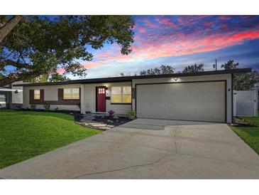 Charming single-story home features a red front door, attached garage and well-maintained front lawn at 3632 E Kaley Ave, Orlando, FL 32812