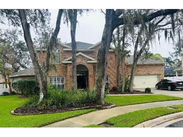 Charming two-story brick home with a well-manicured lawn and mature trees at 382 Raleigh Pl, Oviedo, FL 32765