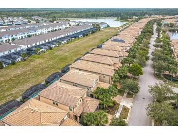 Expansive aerial view of a neighborhood featuring tile roofs, green spaces, and a tranquil lake at 8941 Rhodes St, Kissimmee, FL 34747