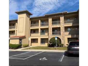 View of a multi-story condo building with stone accents and multiple balconies and a handicap parking spot in front at 912 Charo Pkwy # 214, Davenport, FL 33897