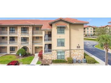 Attractive condo building featuring stone accents, a terracotta roof, and well-maintained landscaping at 912 Charo Pkwy # 214, Davenport, FL 33897