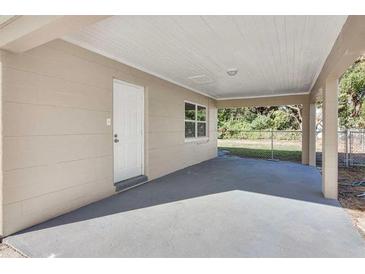 A covered carport showing a concrete foundation, a white exterior door, and a view of the yard beyond at 1797 31St Nw St, Winter Haven, FL 33881