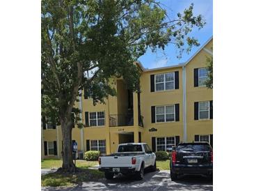 Condominium building with yellow siding, black shutters, and mature landscaping at 2019 Dixie Belle Dr # 2019O, Orlando, FL 32812