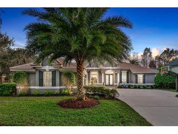 Charming single-story home featuring lush landscaping, a well-manicured lawn, and a prominent palm tree at 3214 Regal Crest Dr, Longwood, FL 32779