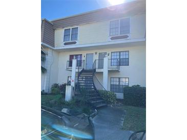 Two-story condo with dark metal staircases and railing, and a yellow facade with cream trim at 6046 Village Cir # 6046, Orlando, FL 32822