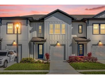 Beautiful two-story townhome with a front entry garage, blue door, and colorful landscaping at 925 Conch Rd, Davenport, FL 33896