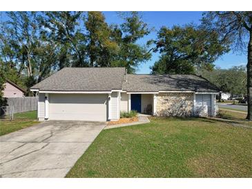 Charming single-story home featuring a stone facade, blue front door, attached garage, and a well-maintained lawn at 103 N Atlas Dr, Apopka, FL 32703