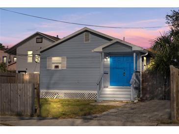 Charming home featuring a blue front door, wood fence, and manicured lawn at 109 Mcquigg Ave, Orlando, FL 32805