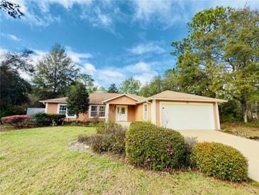 Well-kept single-story home featuring a front lawn with mature landscaping and an attached garage at 14410 Sw 79Th Ter, Ocala, FL 34473