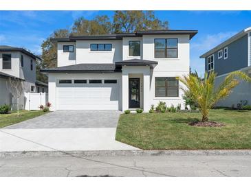 A modern two-story home features a pristine white facade, gray driveway, and black accents at 1809 Simonton Ave, Orlando, FL 32806