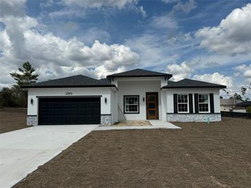 Stunning single-story home featuring a modern design, a black garage door, and an inviting front entrance at 2293 Sw 178Th Lane Rd, Ocala, FL 34473