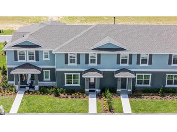 A charming two-story townhome with blue and gray exterior paint, complimented by a well manicured front lawn and walkway at 2680 Gouda Dr, Apopka, FL 32703