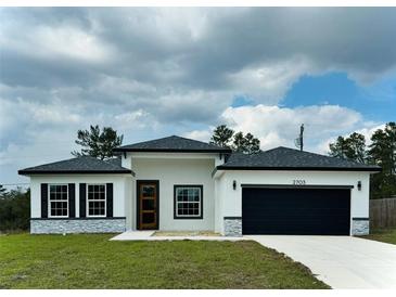 Charming single-story home with a black garage door, gray stone accents, and well-manicured lawn at 2703 Sw 162Nd Street Rd, Ocala, FL 34473