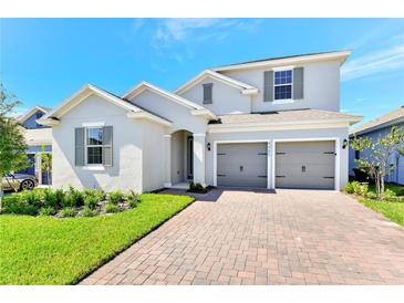 Charming two-story home featuring a brick driveway, manicured lawn, and a two-car garage at 4485 Davos Dr, Clermont, FL 34711