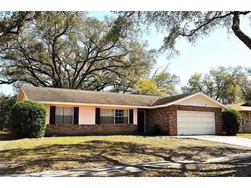 Charming single-story home featuring a brick facade, attached garage, and mature landscaping at 5339 Cypress Dr, Winter Park, FL 32792