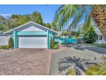 Charming home featuring a brick driveway, manicured bushes, lush palms, and a two-car garage at 721 Glenridge Way, Winter Park, FL 32789