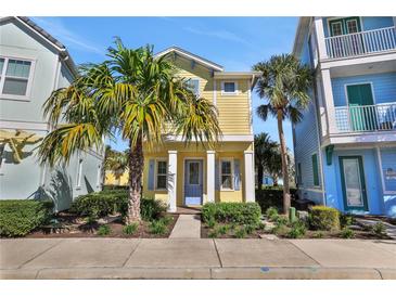 Charming yellow two-story home with blue trim, a well-manicured lawn, and vibrant tropical landscaping at 8005 Flip Flop Way, Kissimmee, FL 34747