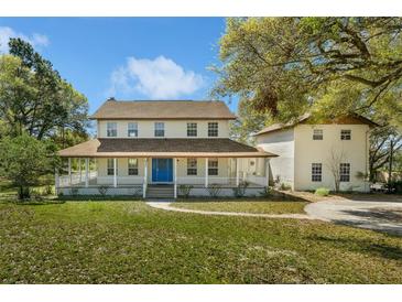 Charming two-story home featuring a full-length front porch and a bright blue front door at 9332 Windy Ridge Rd, Windermere, FL 34786