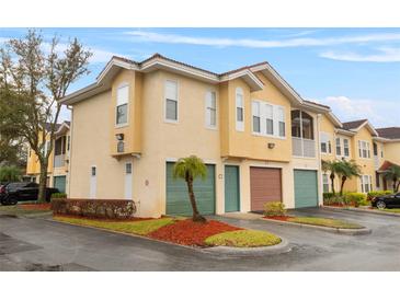 Inviting townhome exterior featuring a two-car garage and well-maintained landscaping at 12008 Villanova Dr # 112, Orlando, FL 32837