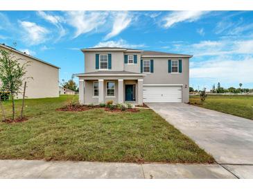 Charming two-story home with a well-manicured lawn, attached two-car garage, and inviting blue front door at 1210 Alstonia Ln, Mount Dora, FL 32757
