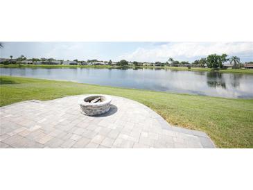 Beautiful backyard features a brick patio with a fire pit overlooking a tranquil lake at 14712 Eagles Crossing Dr, Orlando, FL 32837