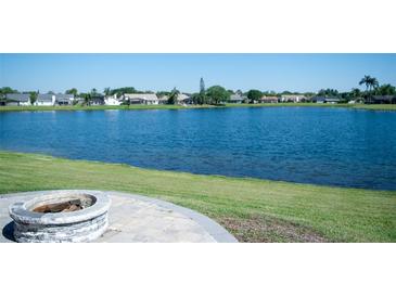 Scenic backyard view with a serene lake and inviting fire pit, perfect for outdoor relaxation and entertaining guests at 14712 Eagles Crossing Dr, Orlando, FL 32837