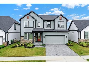 Two-story home boasts a modern exterior with gray siding, stone accents, and a well-manicured front lawn at 17052 Cercis Loop, Clermont, FL 34711