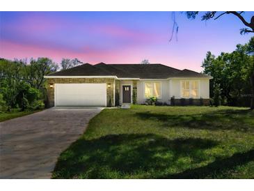 Charming single-story home featuring a two-car garage, stone accents, and a well-manicured lawn at 1870 Blackwelder Rd, De Leon Springs, FL 32130