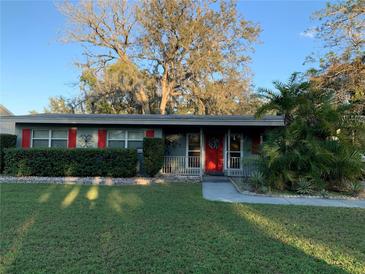 Charming home featuring a well-maintained front yard with lush greenery and a vibrant red front door at 217 Wilmer Ave, Orlando, FL 32811