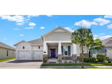 Charming single-story home with a manicured lawn, paver driveway and vibrant blue front door at 5499 Orange Orchard Dr, Winter Garden, FL 34787
