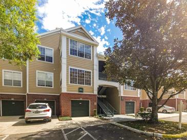 Attractive condo building featuring a brick facade, multiple levels, attached garages, and manicured landscaping at 13037 Mulberry Park Drive Dr # 529, Orlando, FL 32821