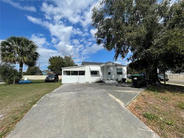 Cozy single-story home with a long driveway, lush tree, and bright, sunny skies at 4005 Clarcona Ocoee Rd, Orlando, FL 32810