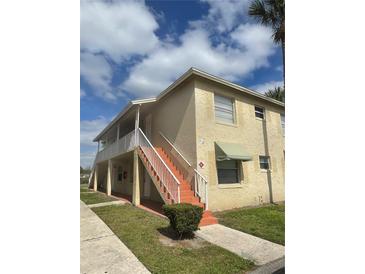 Two-story condo building with stairs leading to the second-floor units under a bright blue cloudy sky at 709 Michigan Ct # 4, St Cloud, FL 34769