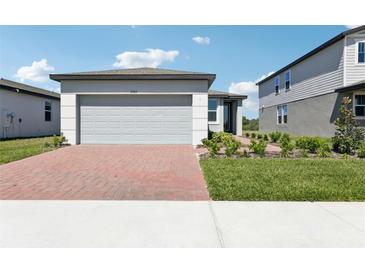 Charming single-story home with a brick driveway, landscaped yard, and attached two-car garage at 2513 Merseyside Ct, Haines City, FL 33844