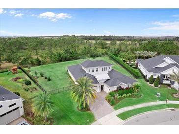 Stunning aerial view of a home with a lush lawn, complemented by mature trees and impeccable landscaping at 8614 Hata St, Orlando, FL 32827