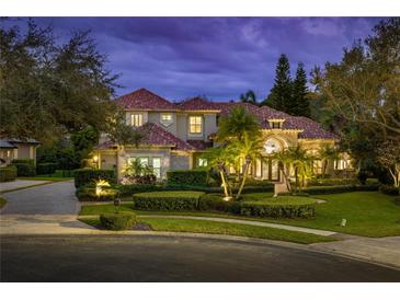 Elegant two-story home featuring a red tile roof, manicured landscaping, and decorative outdoor lighting at 9212 Island Lake Ct, Orlando, FL 32836