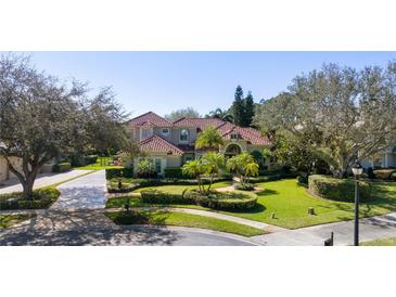 Stately two-story residence showcasing lush landscaping, a red tile roof, and a circular driveway at 9212 Island Lake Ct, Orlando, FL 32836