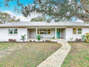 Charming single-story home with a well-manicured lawn, fresh landscaping, and inviting walkway to the turquoise front door at 1510 Live Oak St, New Smyrna Beach, FL 32168