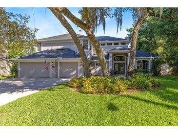 Charming two-story home with a well-manicured lawn and mature trees creating a picturesque setting at 235 Nob Hill Cir, Longwood, FL 32779