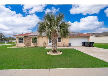 Charming single-story home with well-manicured lawn, palm tree, solar panels and attached garage at 4303 Tomlinson Cir, Orlando, FL 32829