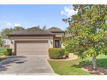 Charming single-story home with a brick driveway, two-car garage, and beautifully landscaped front yard at 556 Grande Dr, Davenport, FL 33837