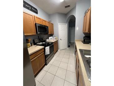 Well-lit kitchen featuring wood cabinets, stainless steel appliances, and neutral countertops at 6466 Cava Alta Dr # 205, Orlando, FL 32835