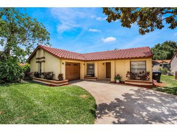 Charming one-story home with well-maintained landscaping, a red tile roof, and a private two-car garage at 8012 S Madeira Ct, Orlando, FL 32836