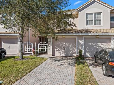 Charming townhome featuring a brick driveway, two-car garage, and inviting gated entrance at 8323 Bella Vida Cir, Davenport, FL 33896