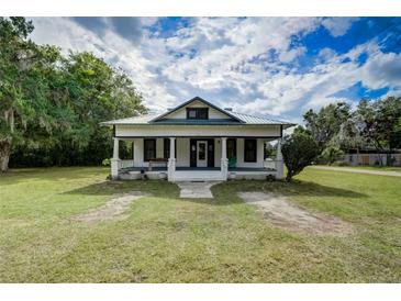 Charming home featuring a covered front porch, white siding, black window trim, and a beautifully landscaped lawn at 3512 Central Ave, Coleman, FL 33521