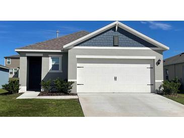 Attached two-car garage with white doors and gray exterior at 3627 Salvia Ct, Tavares, FL 32778