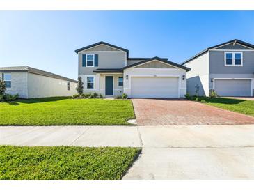 Charming two-story home with a well-manicured lawn and a brick paved driveway on a sunny day at 4514 Windy Oak Way, St Cloud, FL 34772