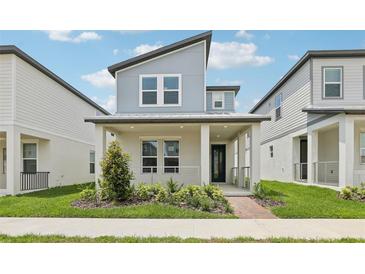 Charming two-story home featuring a quaint front porch, modern architectural details, and neatly manicured landscaping at 5106 Railroad Vine Aly, Winter Garden, FL 34787
